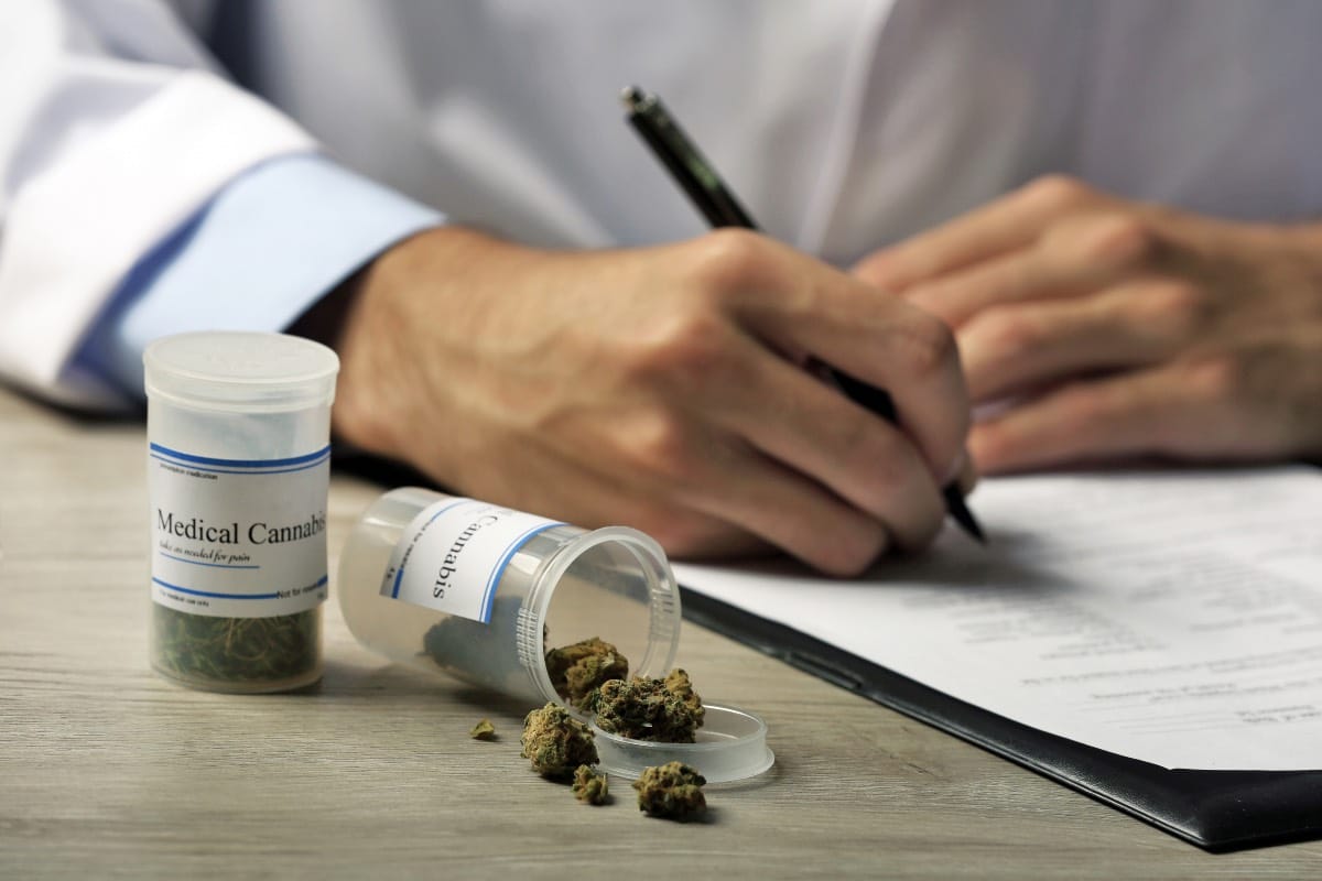 medecin redigeant une ordonnance et un flacon de cannabis medical sur son bureau